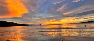 a sunset on the beach with people in the water at Coco Sunset Hills #42 in Coco