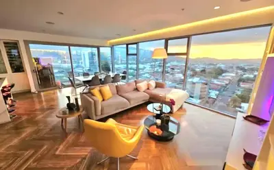 a living room with a couch and a view of a city at Lujo al atardecer en Rohrmoser in San José