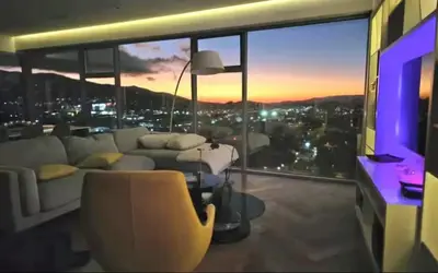 a living room with a couch and a view of a city at Lujo al atardecer en Rohrmoser in San José
