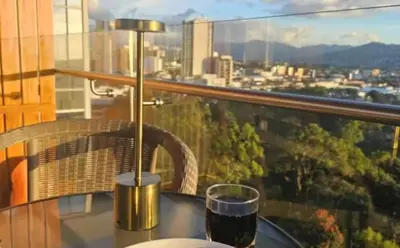 a glass of wine sitting on a table with a view at Lujo al atardecer en Rohrmoser in San José
