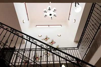 a staircase with a white ceiling and a chandelier at Brisas del Aeropuerto Airport Breezes inn in Heredia