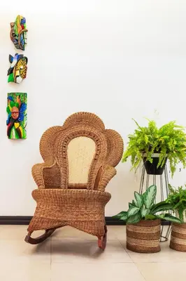 a wicker chair in a room with plants at Brisas del Aeropuerto Airport Breezes inn in Heredia