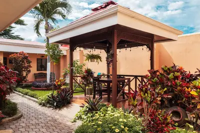 a wooden gazebo with a table in a garden at Brisas del Aeropuerto Airport Breezes inn in Heredia