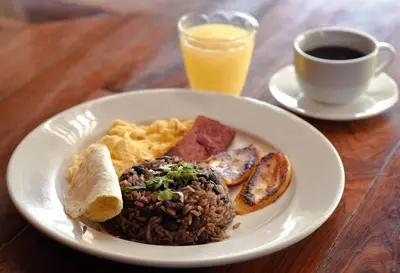 a plate of breakfast food with eggs and a cup of coffee at Brisas del Aeropuerto Airport Breezes inn in Heredia