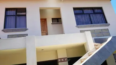 a white building with two windows and a staircase at Morada Kampos in Heredia