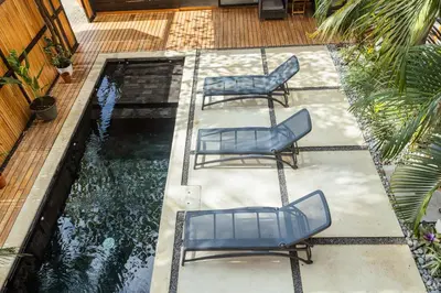 two blue chairs sitting on a patio next to a pond at Casa Swell Boutique Hotel Santa Teresa in Santa Teresa Beach
