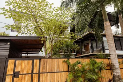 a house with a wooden fence and palm trees at Casa Swell Boutique Hotel Santa Teresa in Santa Teresa Beach
