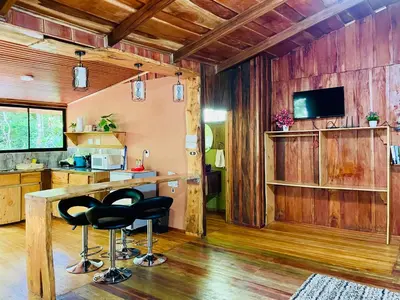 a kitchen with wooden walls and a bar with stools at Cabañas La Montaña in Monteverde Costa Rica