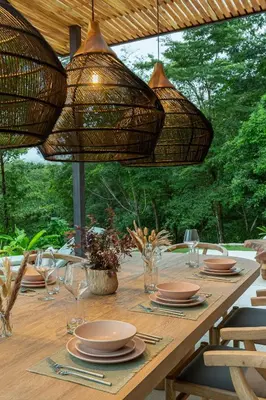a long wooden table with plates and glasses and lights at Villa Koa - Your Tropical Retreat in Santa Teresa Beach
