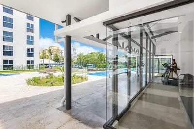an open glass door of a building with a pool at Upstay - Brand New Condo w Pool - Near the Beach in Jacó