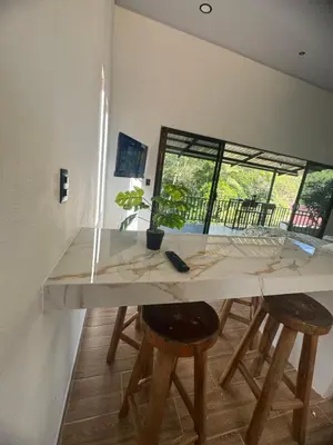 a kitchen with a table with stools and a window at Villa Colibrí a solo 5mins de Playa Carrillo in Hojancha