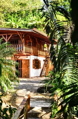 a wooden house with a porch and a staircase at Casa Escondida 10min from Carrillo beach in Arbolito