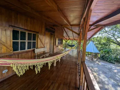 an empty porch of a wooden house with a hammock at Casa Escondida 10min from Carrillo beach in Arbolito