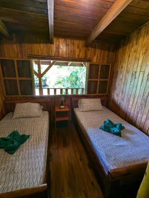 a room with two beds in a wooden cabin at Casa Escondida 10min from Carrillo beach in Arbolito