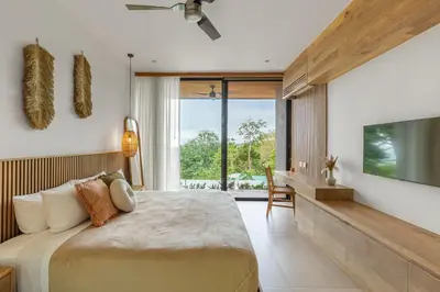 a bedroom with a large bed and a flat screen tv at Casa Roca in Santa Teresa Beach