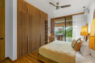 a bedroom with a large bed and a sliding glass door at Casa Roca in Santa Teresa Beach