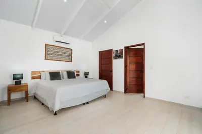 a white bedroom with a bed and a wooden door at 3-BD Home with Pool Near Beach in Brasilito