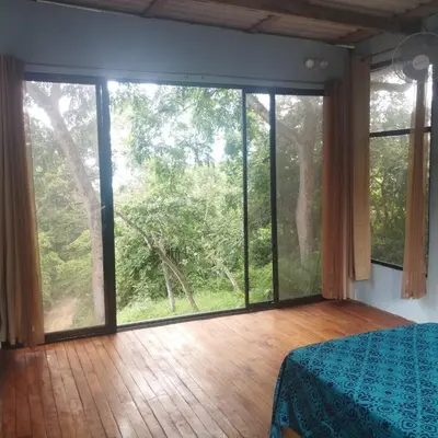 a bedroom with a large window with a view of the forest at Nidos Paradise's in Buenos Aires