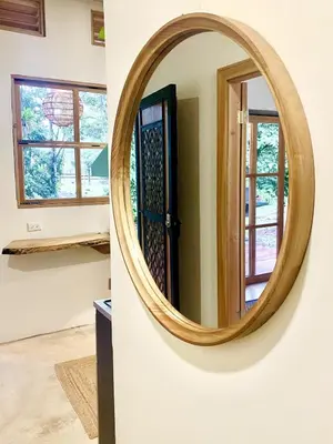 a round wooden mirror on a wall next to a door at Quintaesencia Arte y Naturaleza in Guápiles