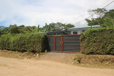 a house with a gate in front of a dirt road at La Dulce Casita in Uvita