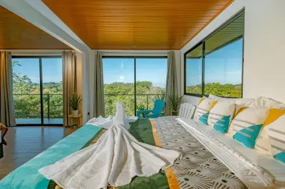 a bedroom with a large bed with a large window at Tardes Doradas in Quepos