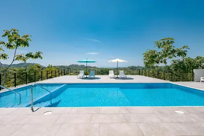 a swimming pool with two chairs and umbrellas at Tardes Doradas in Quepos