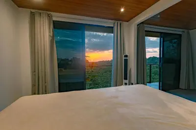 a bedroom with a bed and a window with a sunset at Tardes Doradas in Quepos