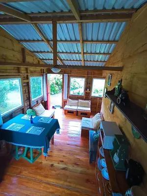 a living room with tables and chairs in a cabin at Finca La Picuda Quetzal Cottage in Cartago