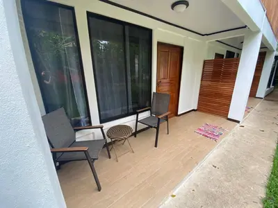 a porch with two chairs and a table and windows at Aracari Garden Hostel in Tortuguero