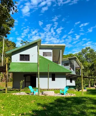 a house with a green roof and two blue chairs at Aracari Eco Lodge in Corazón de Jesús