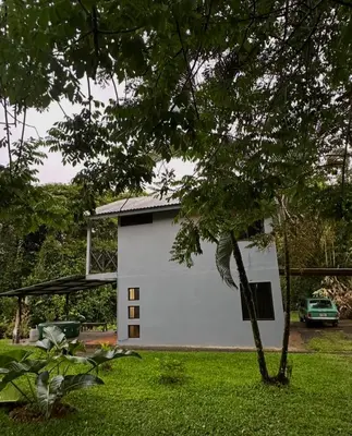a white building in a yard with a tree at Aracari Eco Lodge in Corazón de Jesús