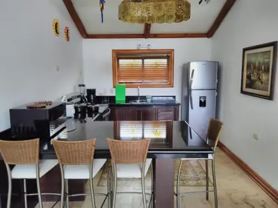 a kitchen with a black counter and a refrigerator at Casa Caletas Boutique Hotel in Puerto Coyote