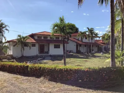 a house with palm trees in front of it at Casa Caletas Boutique Hotel in Puerto Coyote