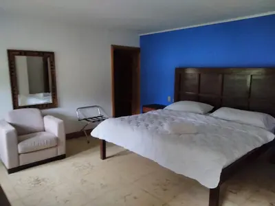 a bedroom with a large bed and a chair at Casa Caletas Boutique Hotel in Puerto Coyote