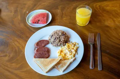 a plate of breakfast food with sausage and toast at Hotel Tamarindo INN - 1 mi to Tamarindo Beach in Tamarindo
