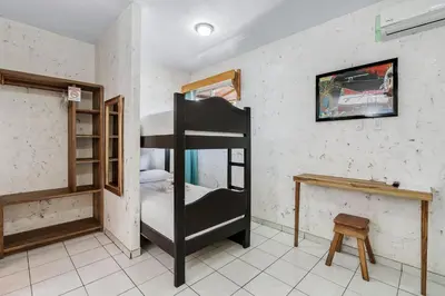 a room with two bunk beds and a table at Hotel Tamarindo INN - 1 mi to Tamarindo Beach in Tamarindo