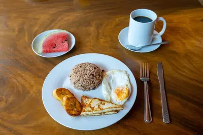 a white plate with breakfast foods and a cup of coffee at Hotel Tamarindo INN - 1 mi to Tamarindo Beach in Tamarindo