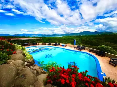 a swimming pool with flowers and mountains in the background at Vista Condor Lodge in Puerto Viejo