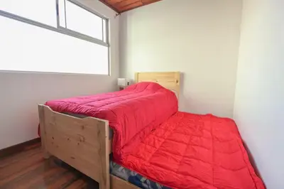 a bed with a red comforter in a room with a window at Bright and central apartment near Plaza del Sol in Guayabos