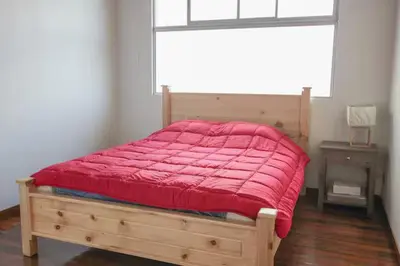 a bedroom with a bed with a red comforter and a window at Bright and central apartment near Plaza del Sol in Guayabos