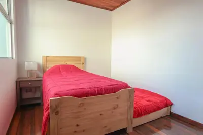 a bedroom with a wooden bed with a red blanket at Bright and central apartment near Plaza del Sol in Guayabos