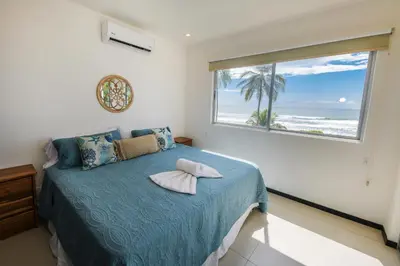 a bedroom with a bed with a view of the ocean at Beautiful beachfront condo, amazing pool in Bejuco