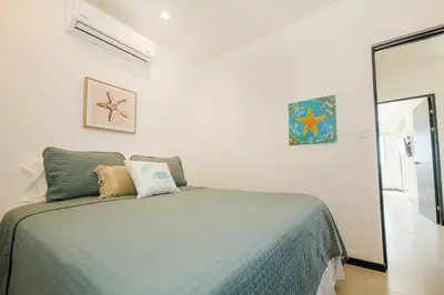 a bedroom with a bed with a green comforter at Beautiful beachfront condo, amazing pool in Bejuco