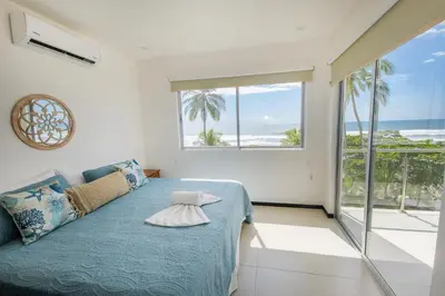 a bedroom with a bed with a view of the ocean at Beautiful beachfront condo, amazing pool in Bejuco