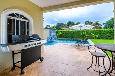 a backyard with a grill and a table and a pool at Villa Sirena Del Mar by Vacation Pura Vida in Bejuco