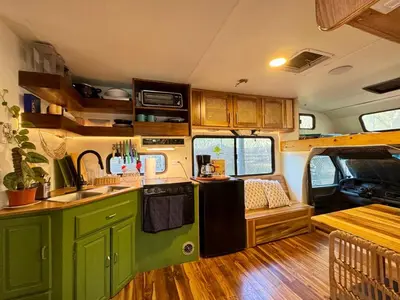 an rv kitchen with green cabinets and a table at La VanDida, Camper house in Paraíso