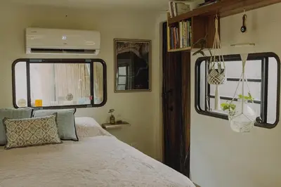 a bedroom with a bed and two windows in an rv at La VanDida, Camper house in Paraíso
