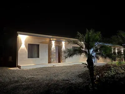 a house with a palm tree in front of it at night at Verde Armonía Lodge in Naranjito