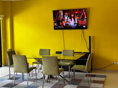 a dining room with yellow walls and a tv on the wall at Primium Jaco Bay in Jacó