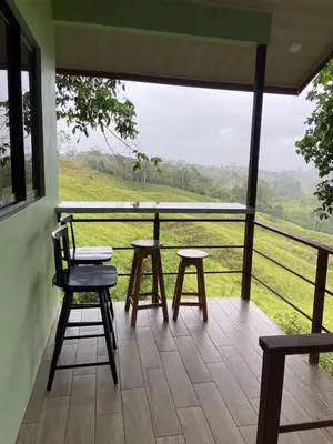 a porch with chairs and tables and a view of a field at Casita El Perezoso in San Rafael